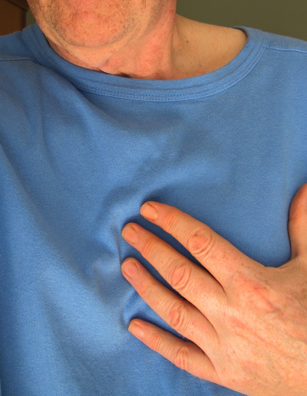 man in blue shirt with hand over heart