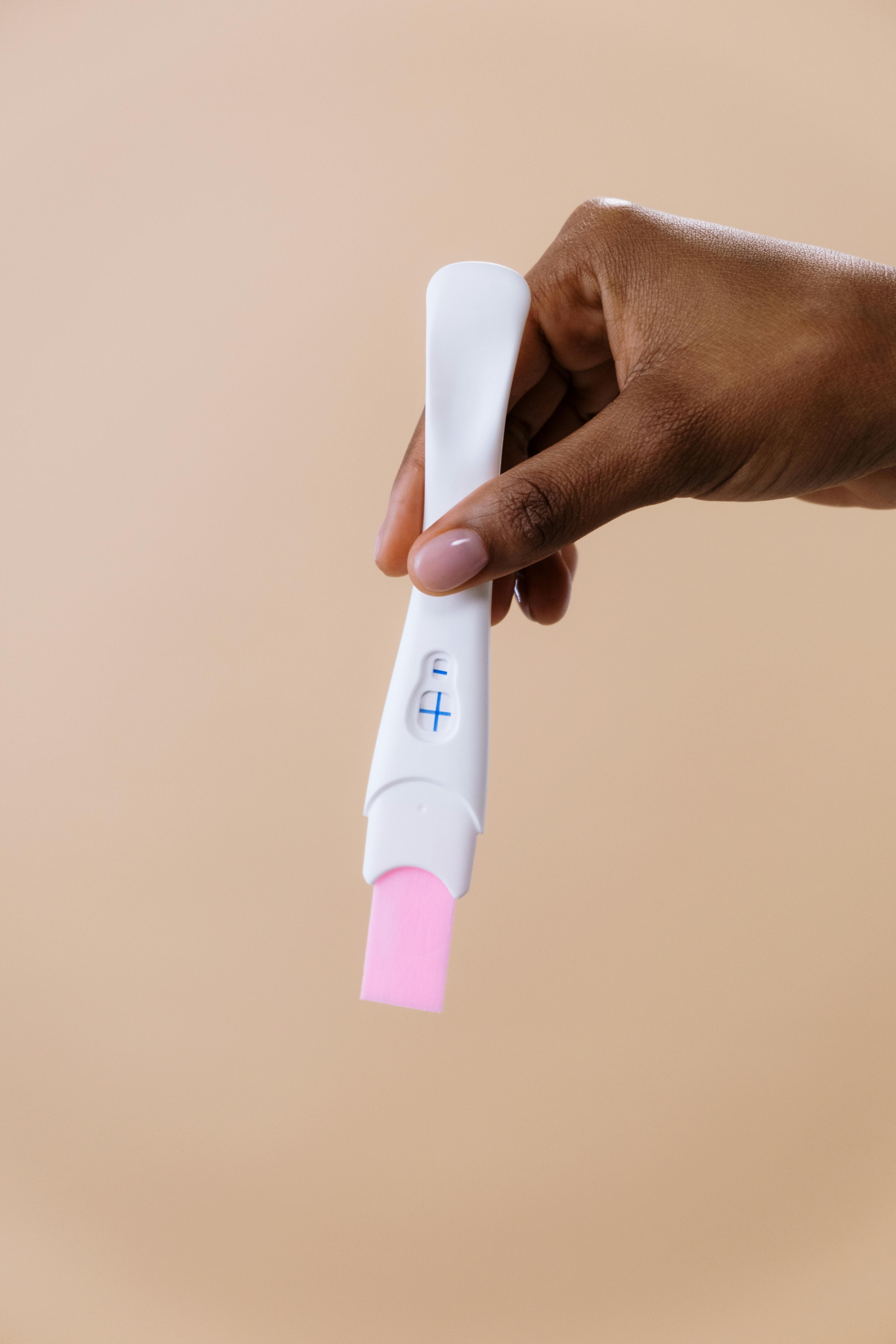 woman's hand holding pregnancy test