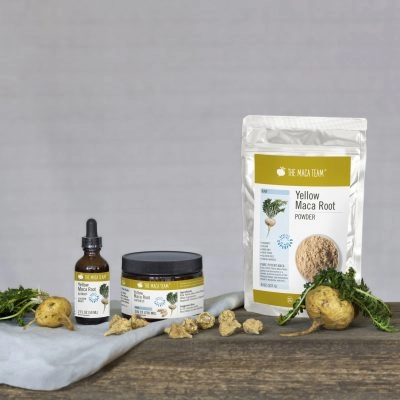 whole yellow maca roots and yellow maca products on wooden table - powder, capsules, and liquid extract
