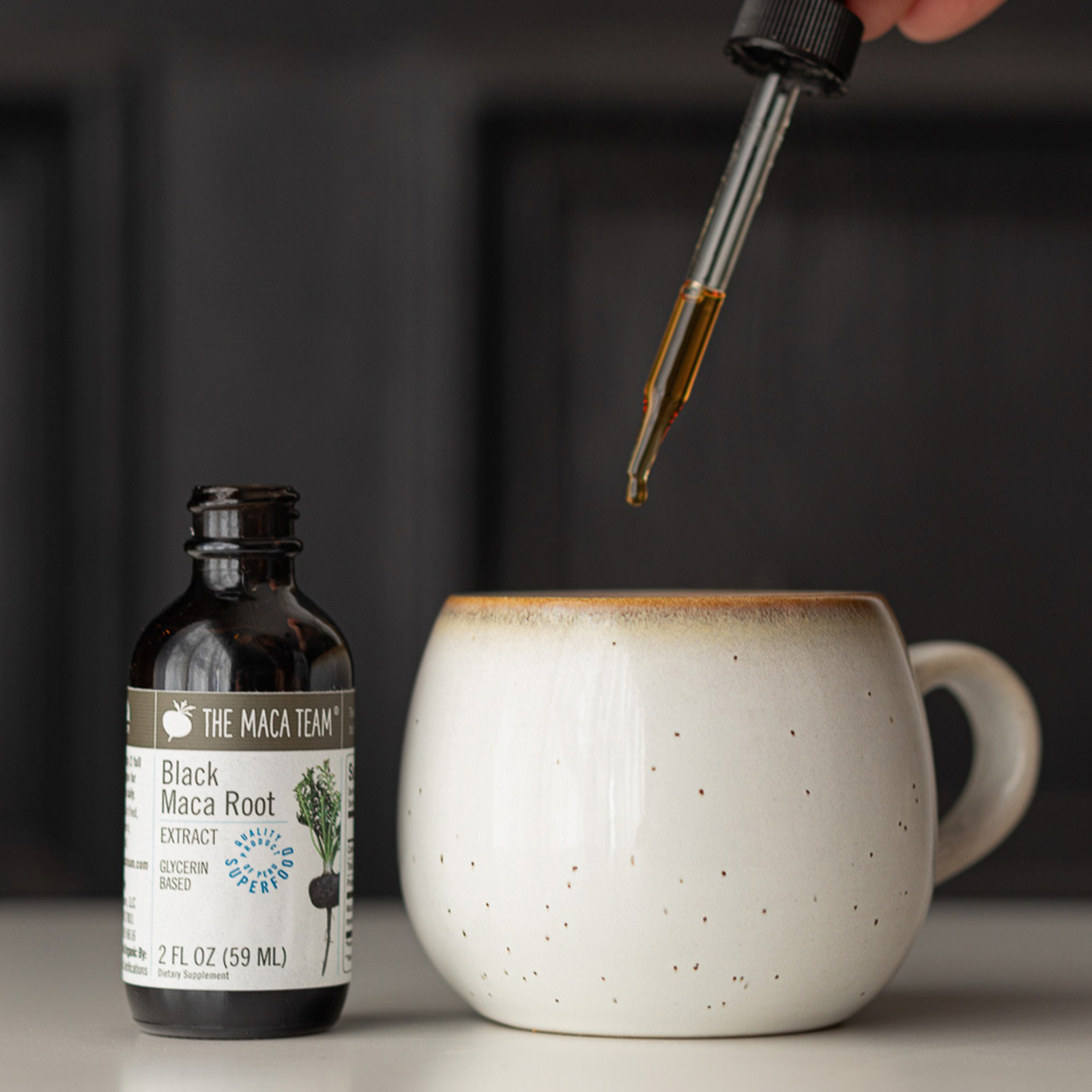 Black Maca Extract from The Maca Team beside a cup